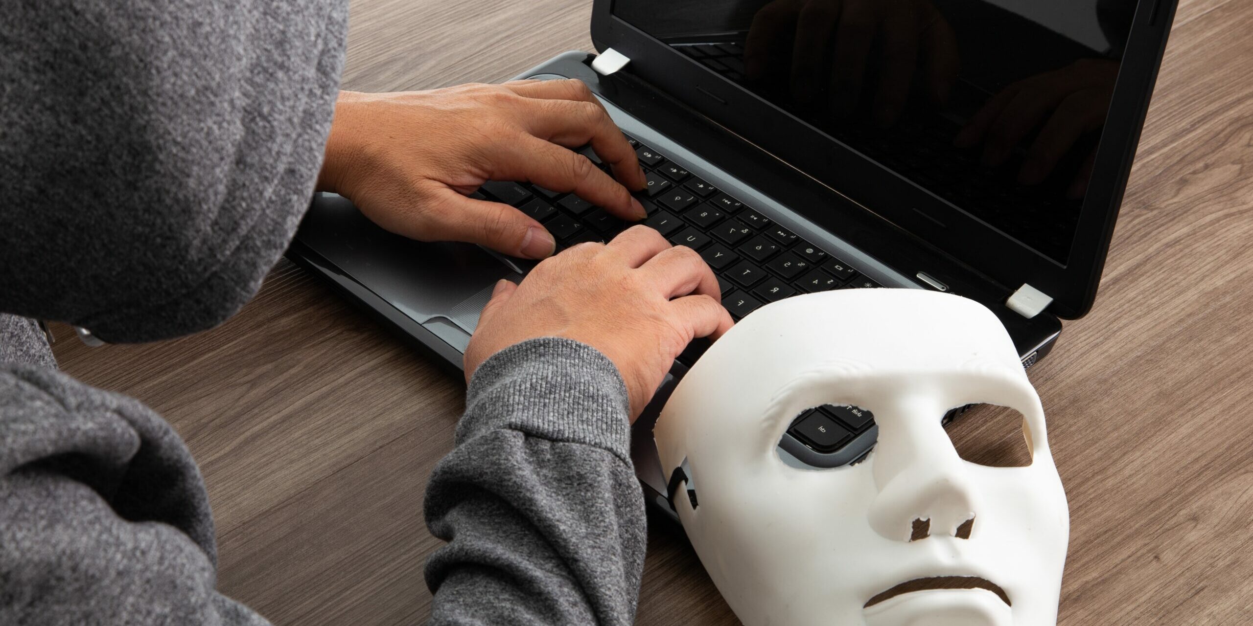 Thief hacker in mask stealing personal information from laptop