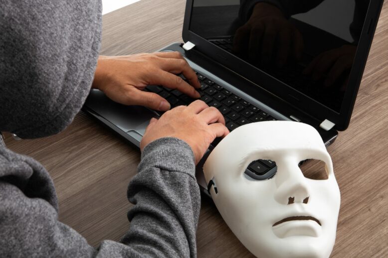Thief hacker in mask stealing personal information from laptop